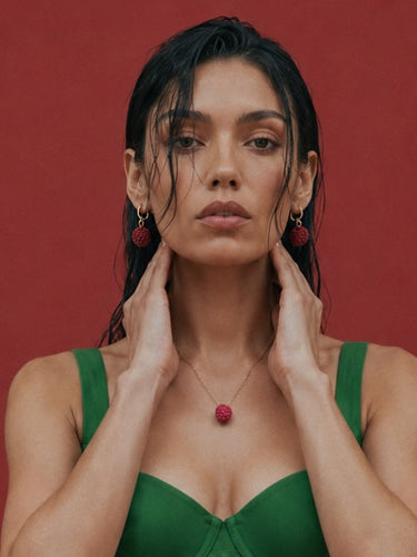 Modelo con pendientes de aro Manitique con colgante de frambuesa realista, luciendo un conjunto veraniego y elegante.